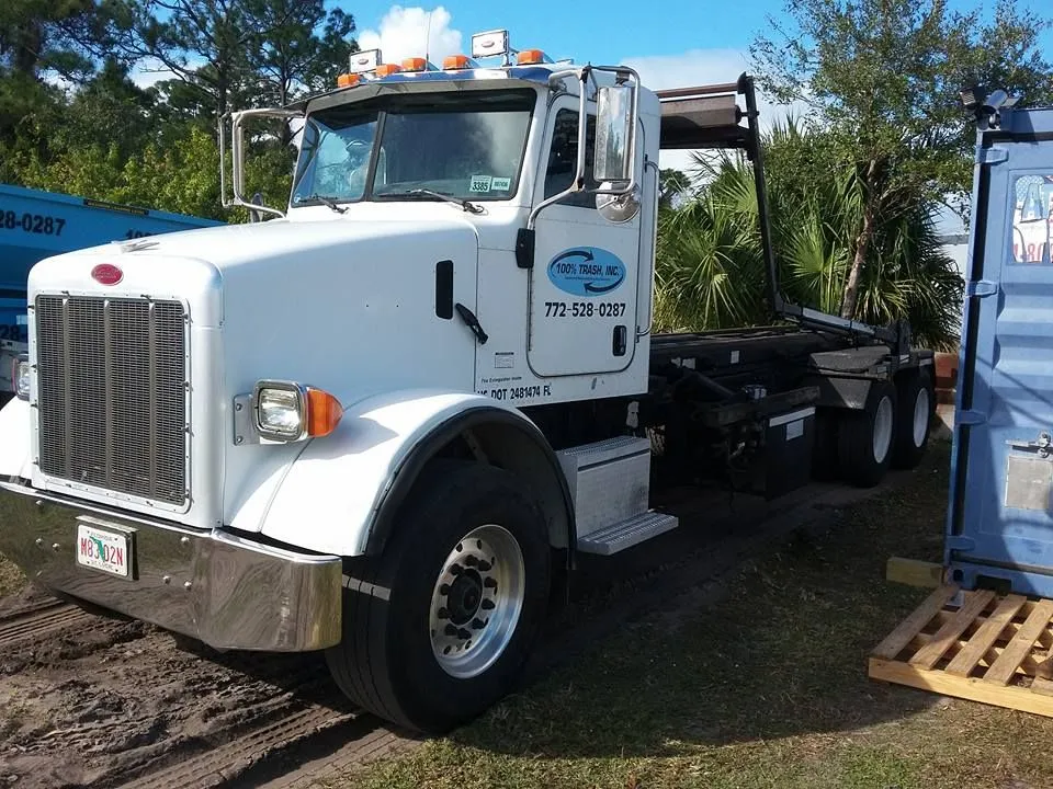 White truck beside blue shipping container outdoors.