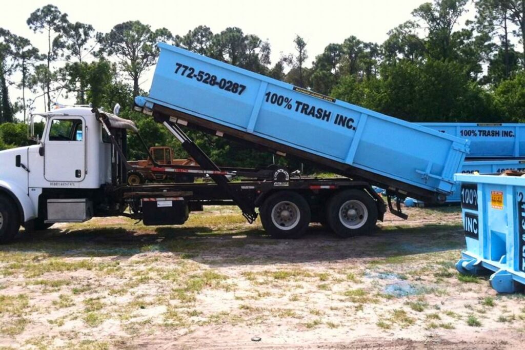 Truck with blue waste container unloading outdoors