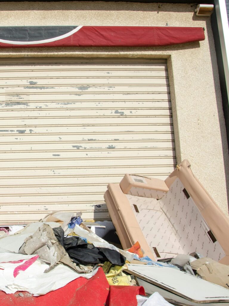 Discarded sofa and garbage by garage door