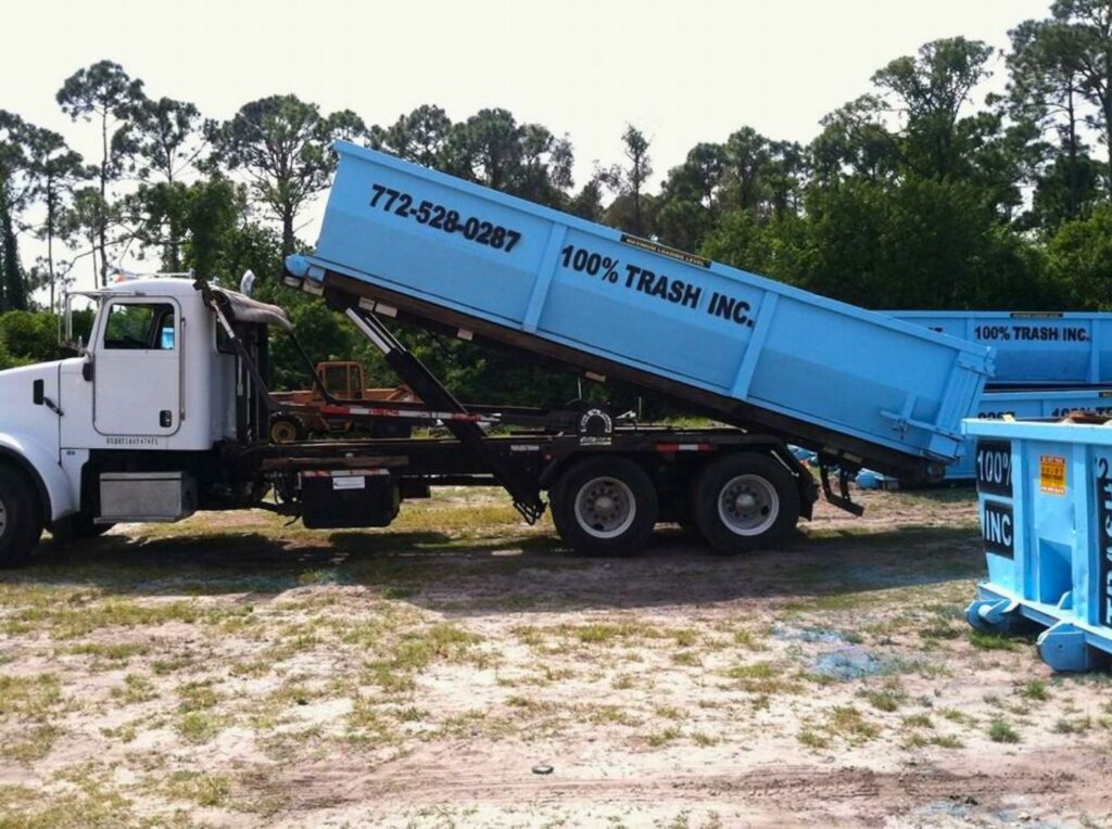 Truck with blue dumpster in a field