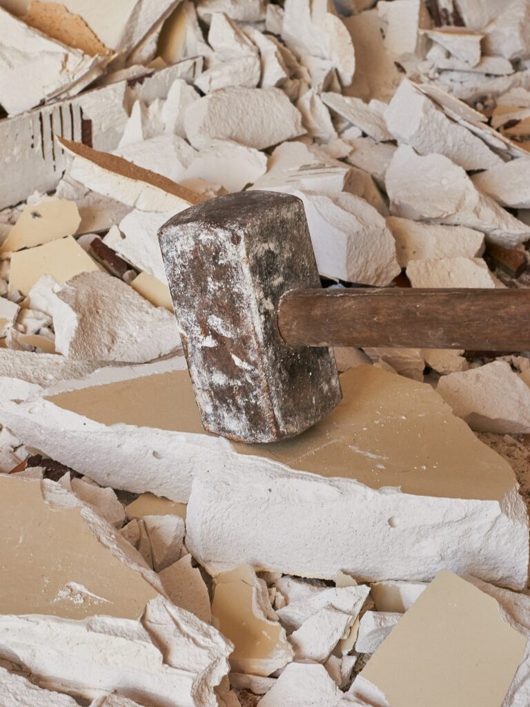 Sledgehammer on broken drywall debris pile.