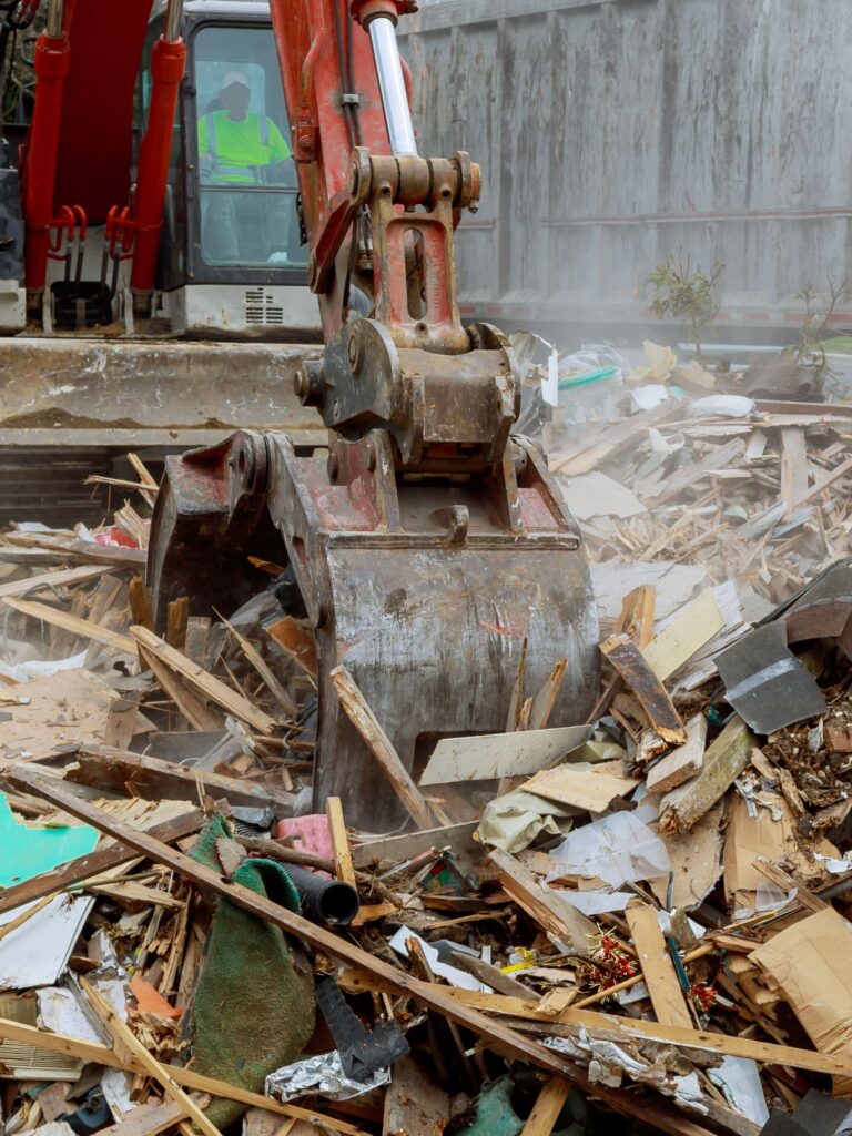 Excavator clearing construction debris at site
