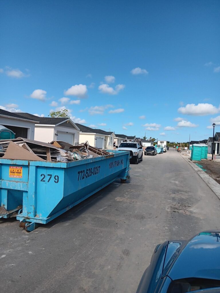 Construction site with blue dumpster on street.