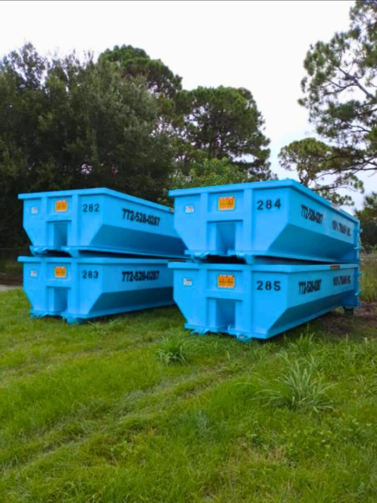 Four blue dumpsters in green grassy area